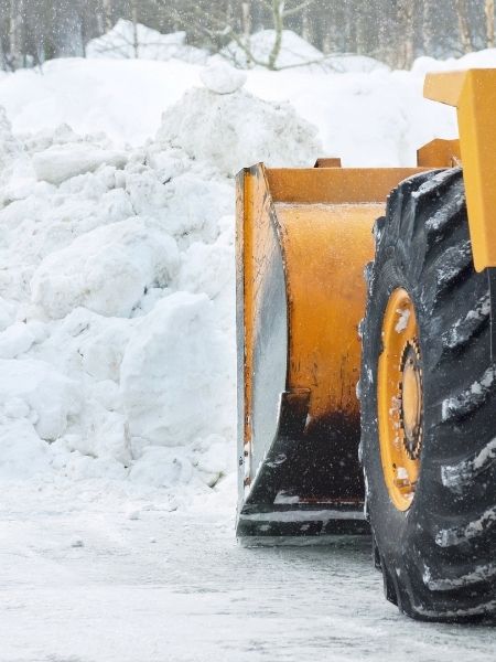 tractor dumping bucket of snow from parking lot